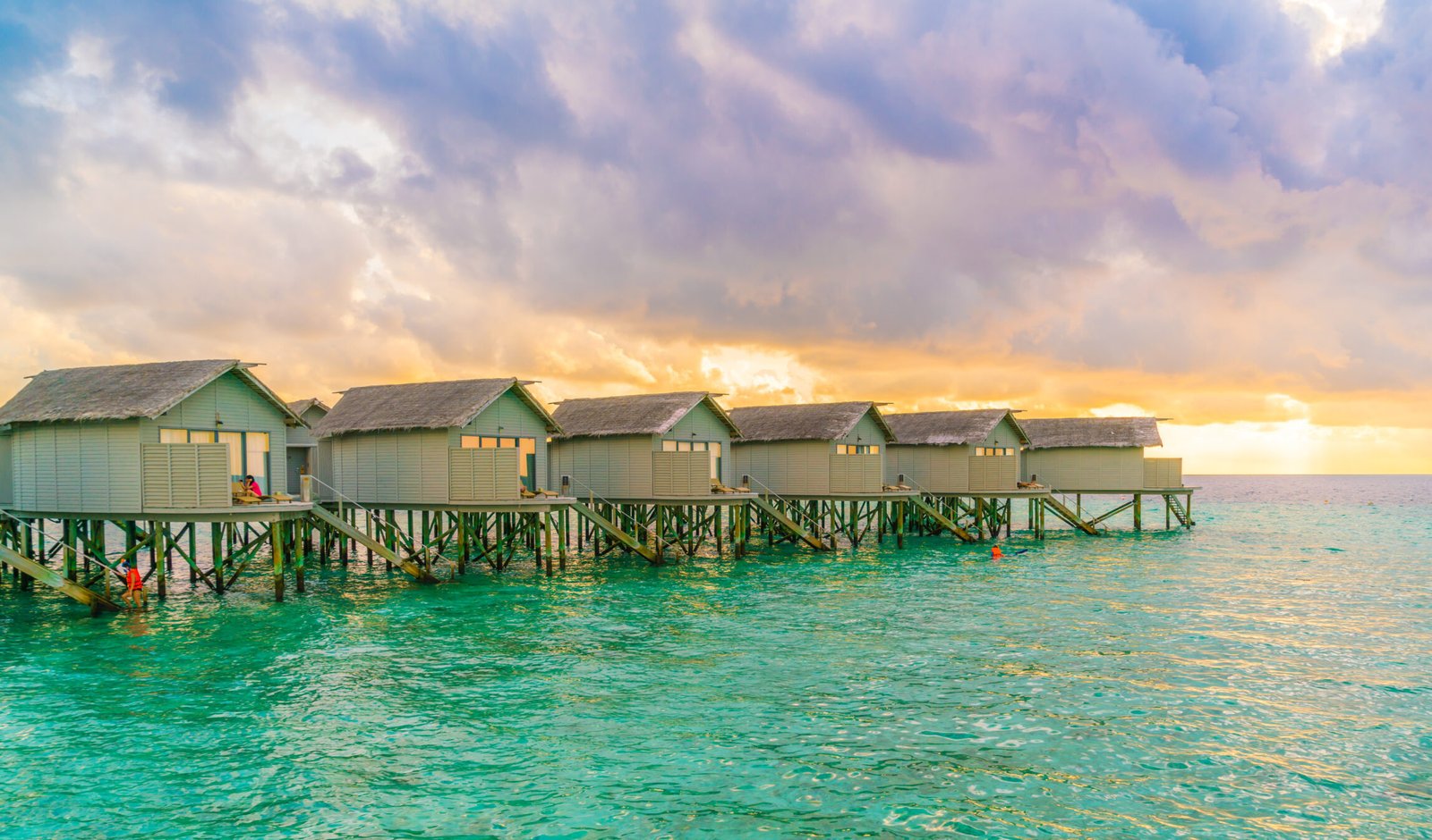 relaxing huts built crystal clear tropical waters stunning sunset sky scaled e1771654503871